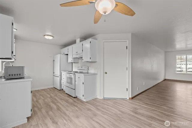 a kitchen with white cabinets and wooden floor