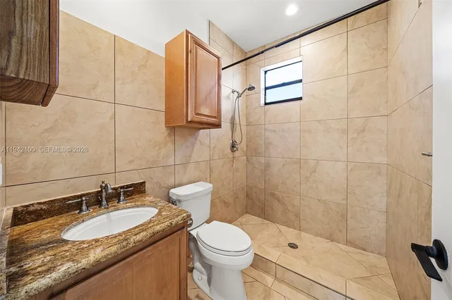 a bathroom with a granite countertop sink toilet and shower