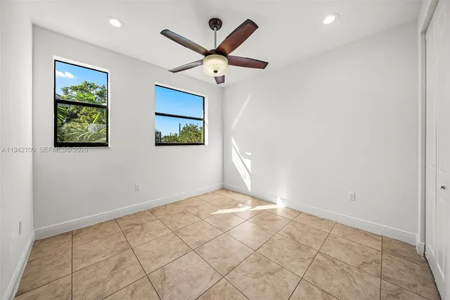 an empty room with windows and fan