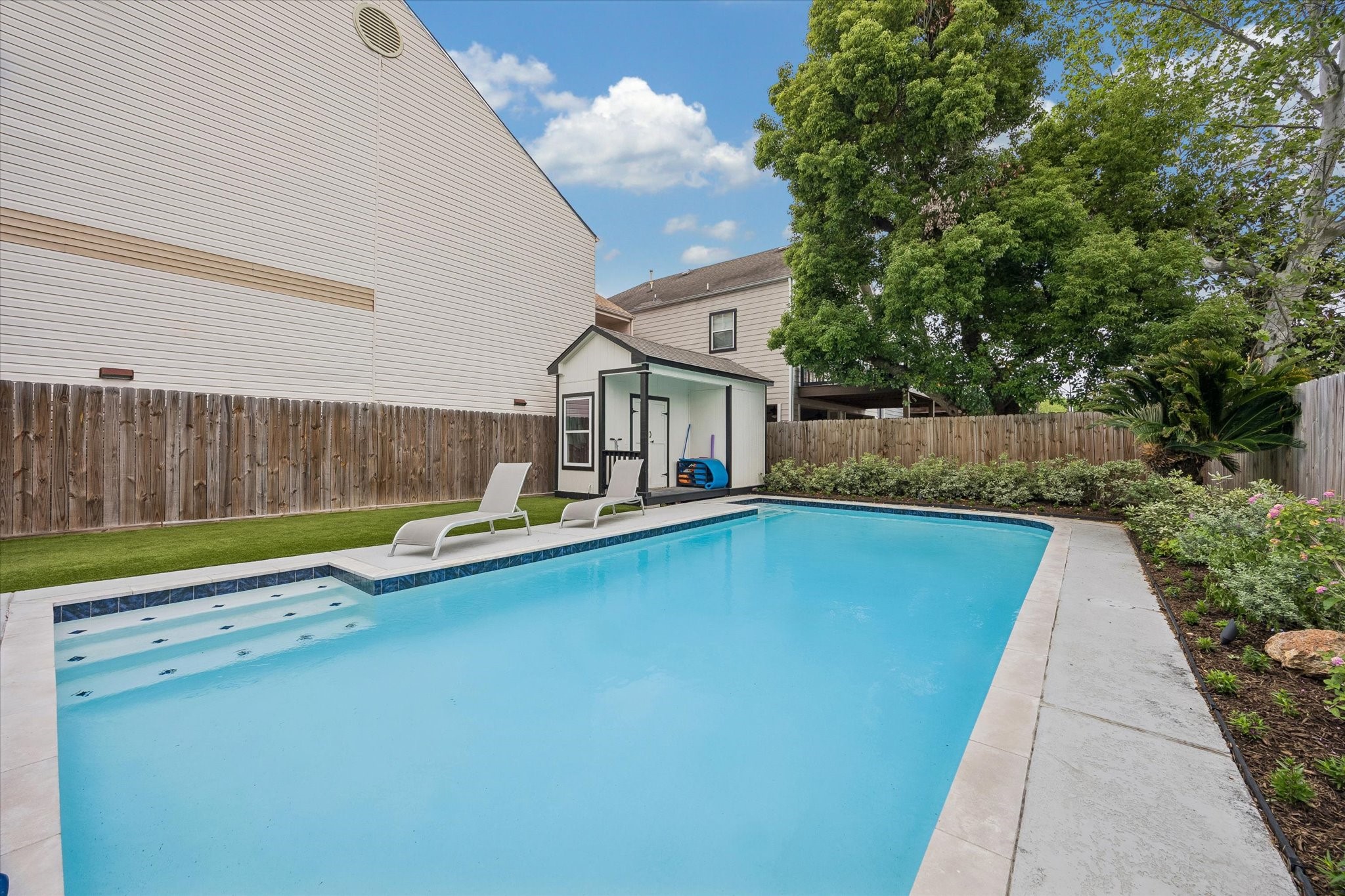 1420 Indiana Street Houston, TX 77006 - Photo 28 of 31 This backyard features a spacious in-ground pool perfect for relaxation. The area is enclosed by a wooden fence and surrounded by well-maintained landscaping, offering privacy and a serene atmosphere. A small shed or pool house is also present, providing additional storage or utility space.