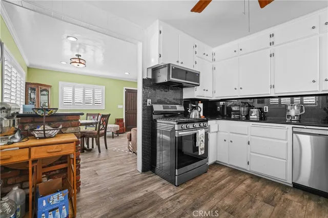 a kitchen with stainless steel appliances granite countertop a stove a sink a refrigerator and white cabinets