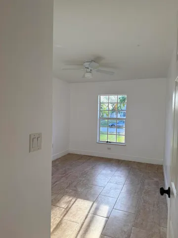an empty room with windows and ceiling fan