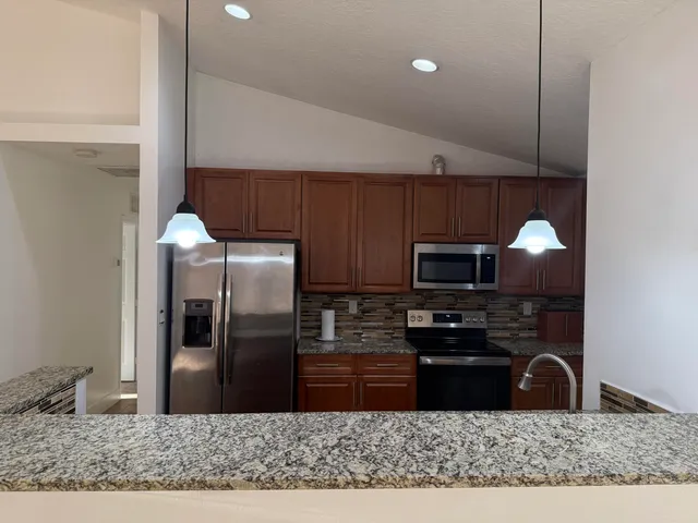 a kitchen with stainless steel appliances granite countertop a refrigerator a stove a sink and a microwave