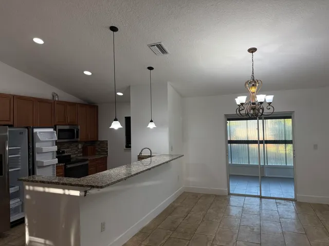 a kitchen with kitchen island granite countertop a refrigerator a sink a stove a microwave and island