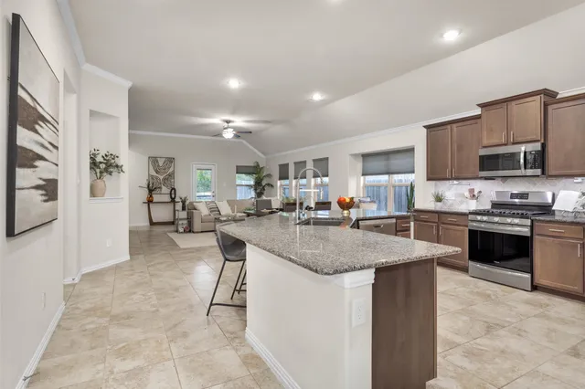 a kitchen with stainless steel appliances granite countertop a stove top oven a sink a dining table and chairs