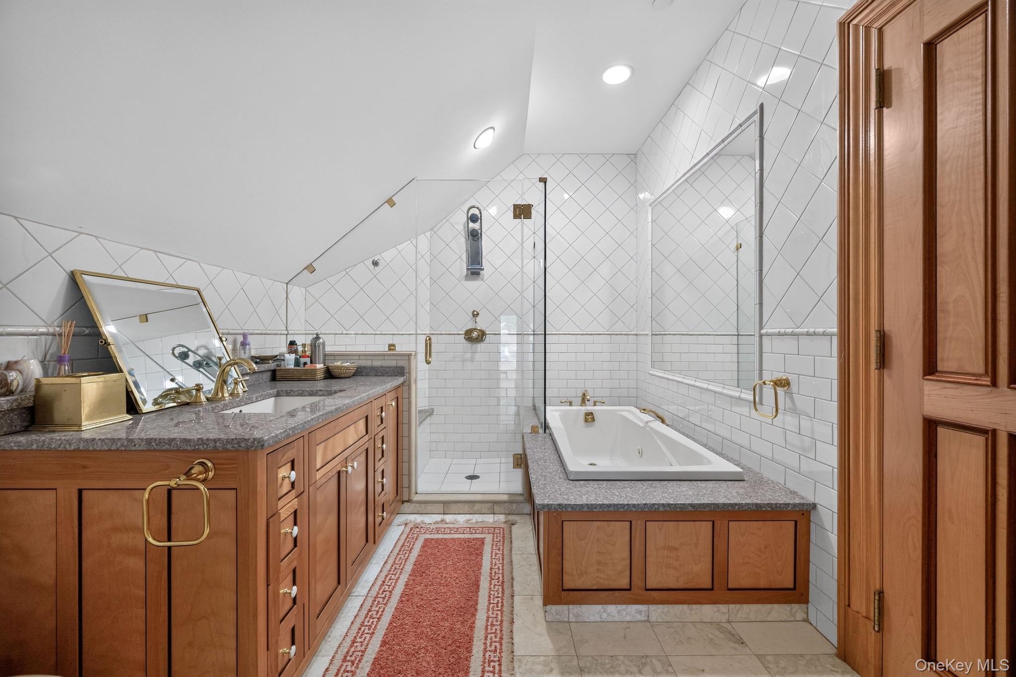 23 Inningwood Road Ossining, NY 10562 - Photo 40 of 50 Bathroom featuring a granite-topped vanity with brass hardware, a built-in soaking tub, and a separate glass-enclosed shower with subway tile surround
