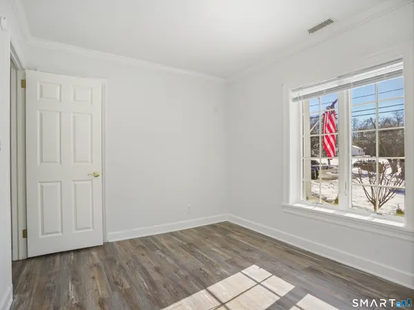 a view of an empty room with window and wooden floor