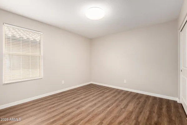 an empty room with wooden floor cabinet and windows