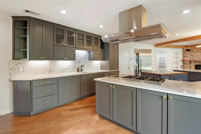 a large kitchen with stainless steel appliances kitchen island granite countertop a large counter top and wooden floors