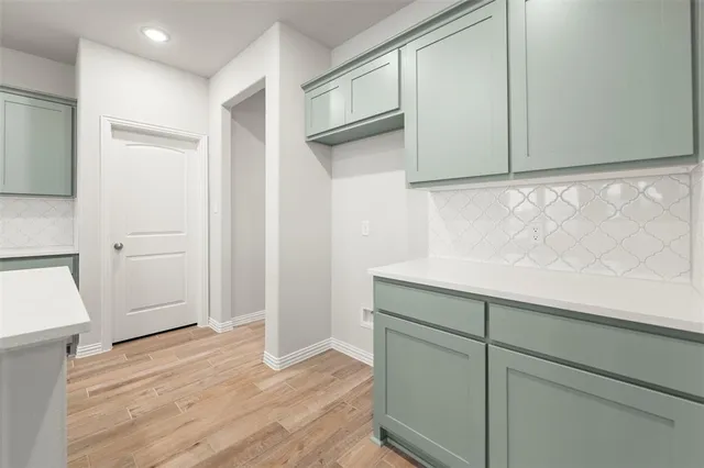 an empty room with wooden floor a ceiling fan a fireplace and windows