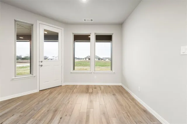 a view of an empty room with a fireplace and wooden floor
