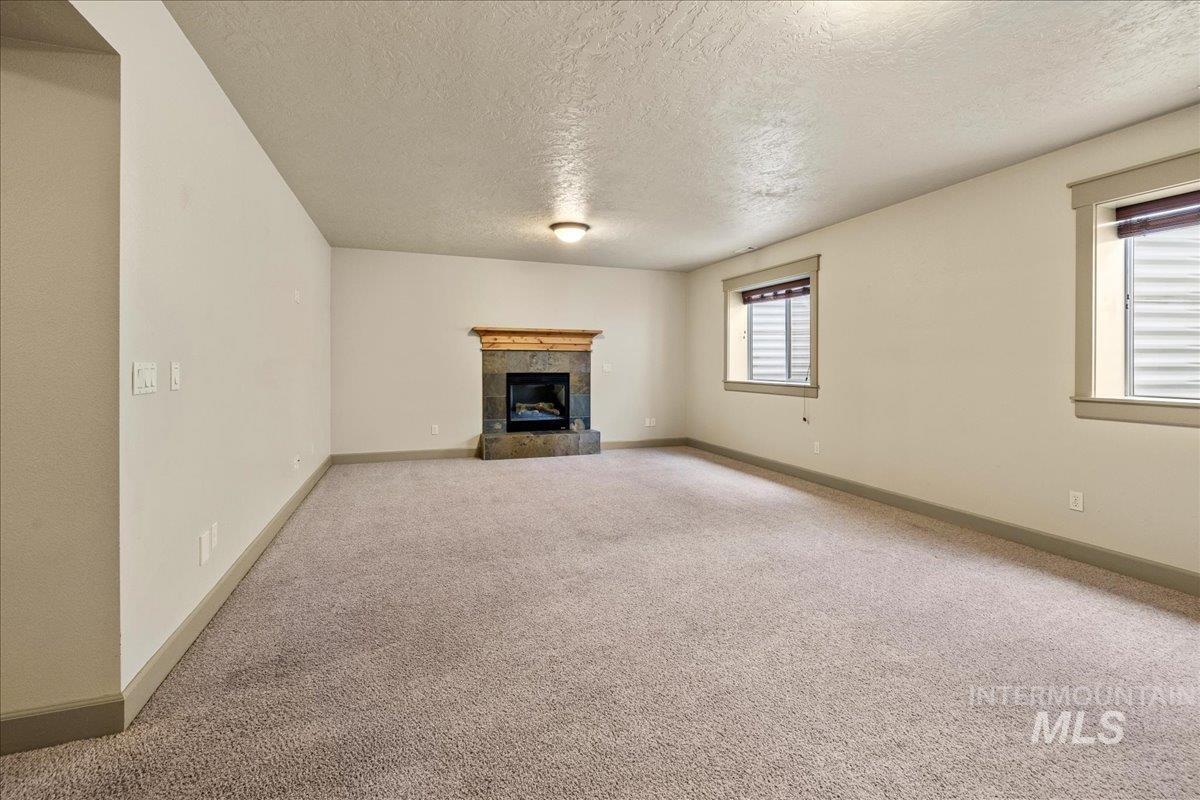 1063 West Hitchcock Street Meridian, ID 83646 - Photo 29 of 50 Unfurnished living room featuring a textured ceiling, carpet, and a fireplace