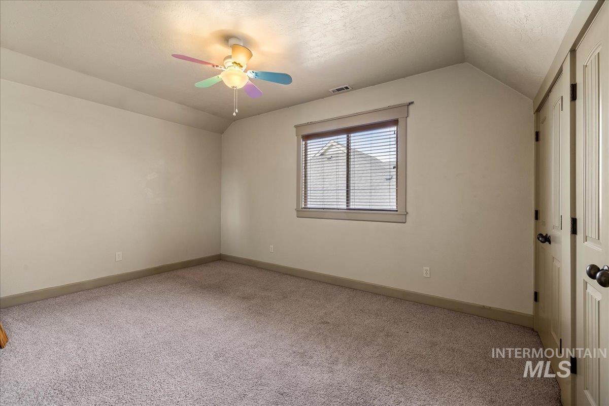 1063 West Hitchcock Street Meridian, ID 83646 - Photo 35 of 50 Empty room with lofted ceiling, a textured ceiling, light carpet, and ceiling fan