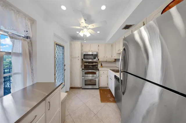 a kitchen with stainless steel appliances granite countertop a refrigerator a stove and a sink