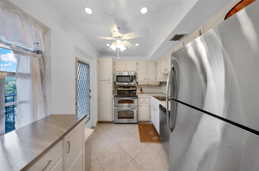 a kitchen with stainless steel appliances granite countertop a refrigerator a stove and a sink