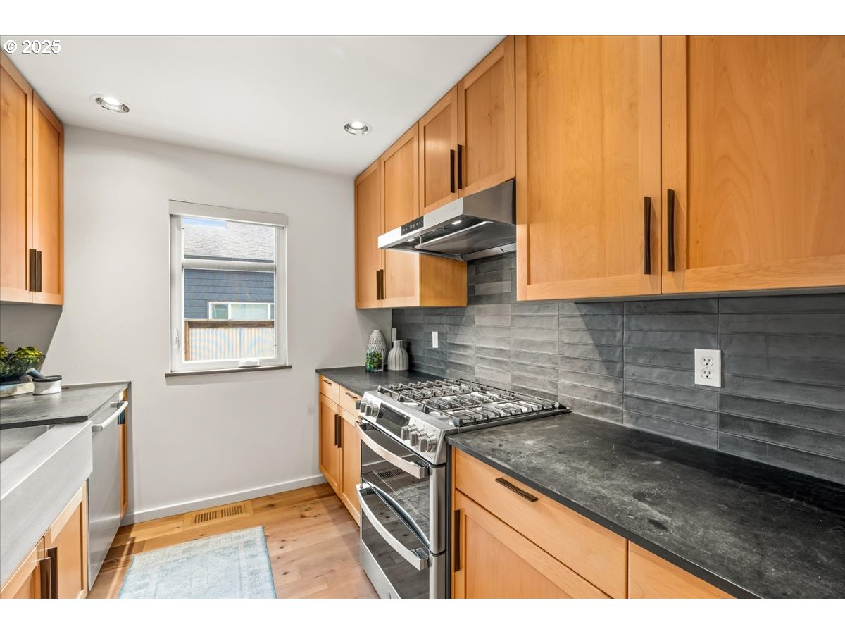 8316 Southeast 7th Avenue Portland, OR 97202 - Photo 11 of 44 a kitchen with stainless steel appliances granite countertop a stove a sink and a microwave