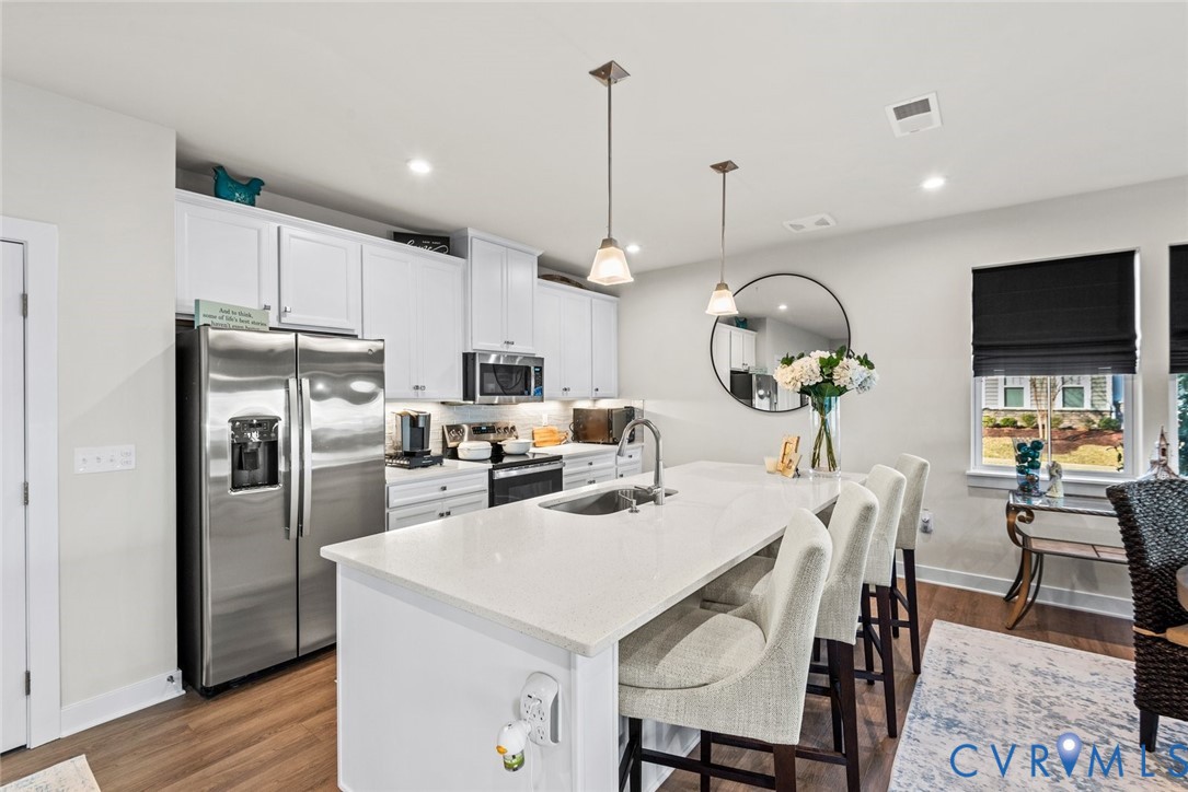 6655 Citory Way, Unit 103 Moseley, VA 23120 - Photo 12 of 48 a kitchen with stainless steel appliances kitchen island granite countertop a dining table chairs and a refrigerator