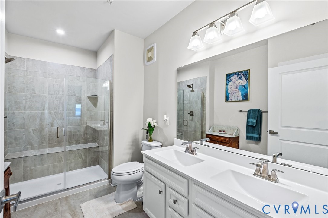 6655 Citory Way, Unit 103 Moseley, VA 23120 - Photo 18 of 48 a bathroom with a toilet a sink a glass door a shower a mirror and vanity