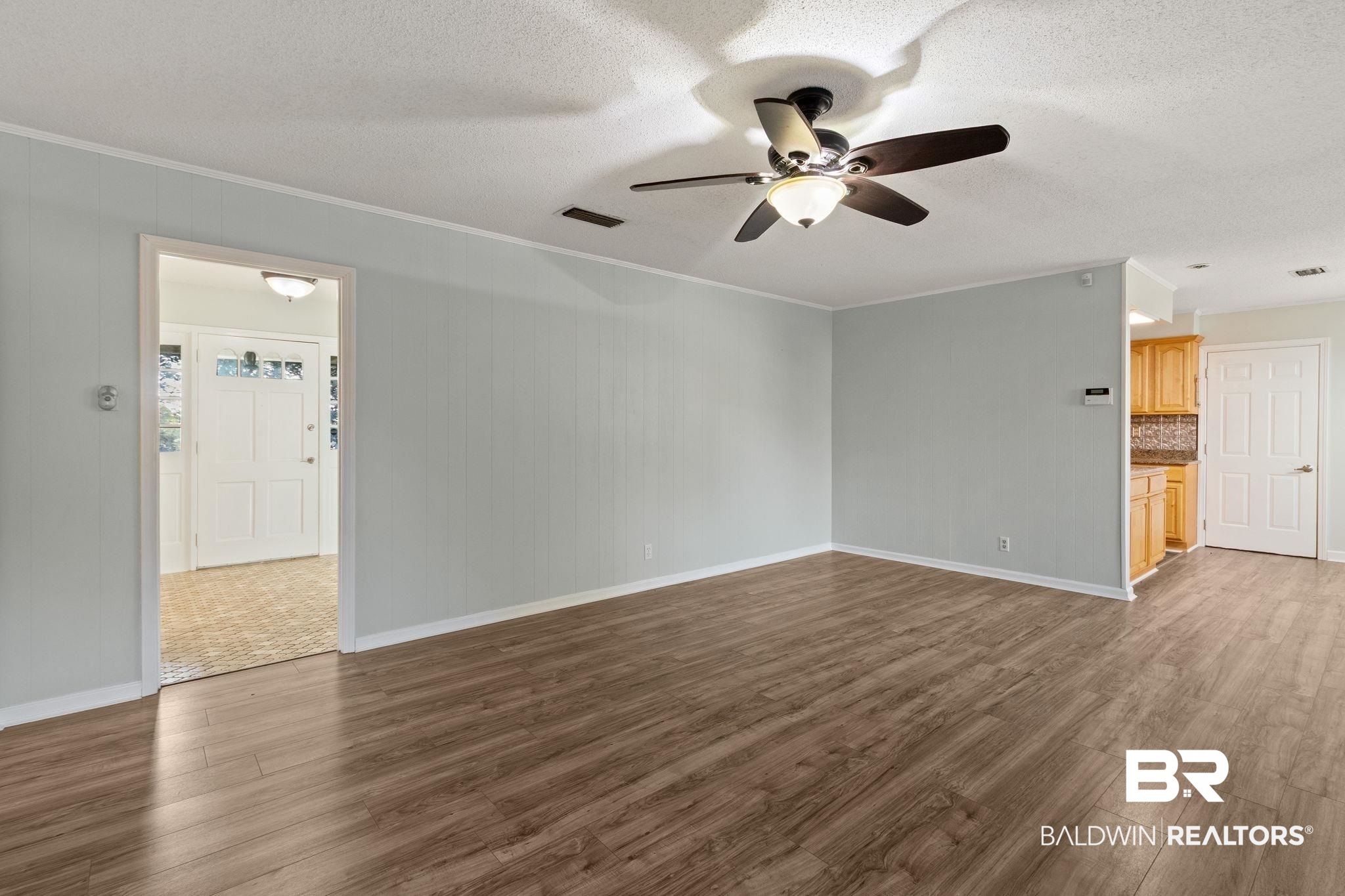 3864 Leroy Stevens Road Mobile, AL 36619 - Photo 6 of 33 Unfurnished living room with a textured ceiling, dark wood-type flooring, a ceiling fan, and crown molding