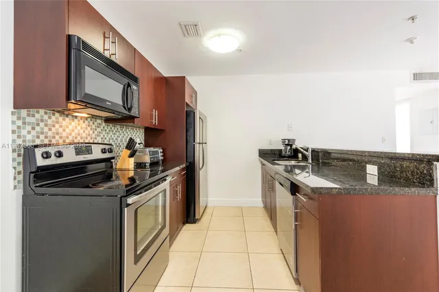 a kitchen with stainless steel appliances granite countertop a stove a sink and a microwave