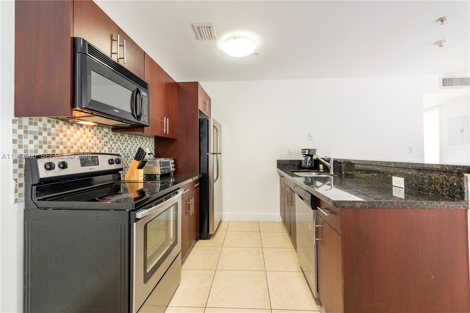 4147 Stirling Road, Unit 301 Dania Beach, FL 33314 - Photo 2 of 12 a kitchen with stainless steel appliances granite countertop a stove a sink and a microwave