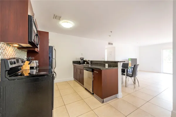 a kitchen with stainless steel appliances granite countertop a sink and a refrigerator