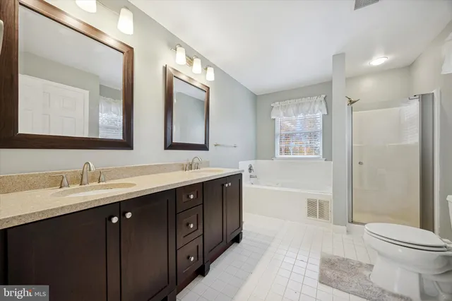 a spacious bathroom with a double vanity sink toilet mirror and shower