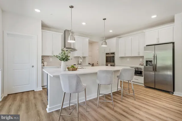 a kitchen with stainless steel appliances a dining table chairs stove refrigerator and cabinets