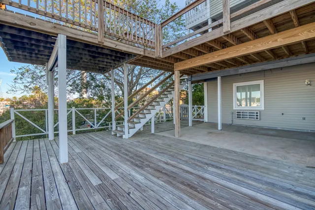 a view of a roof deck with table and chairs a barbeque with wooden floor and fence