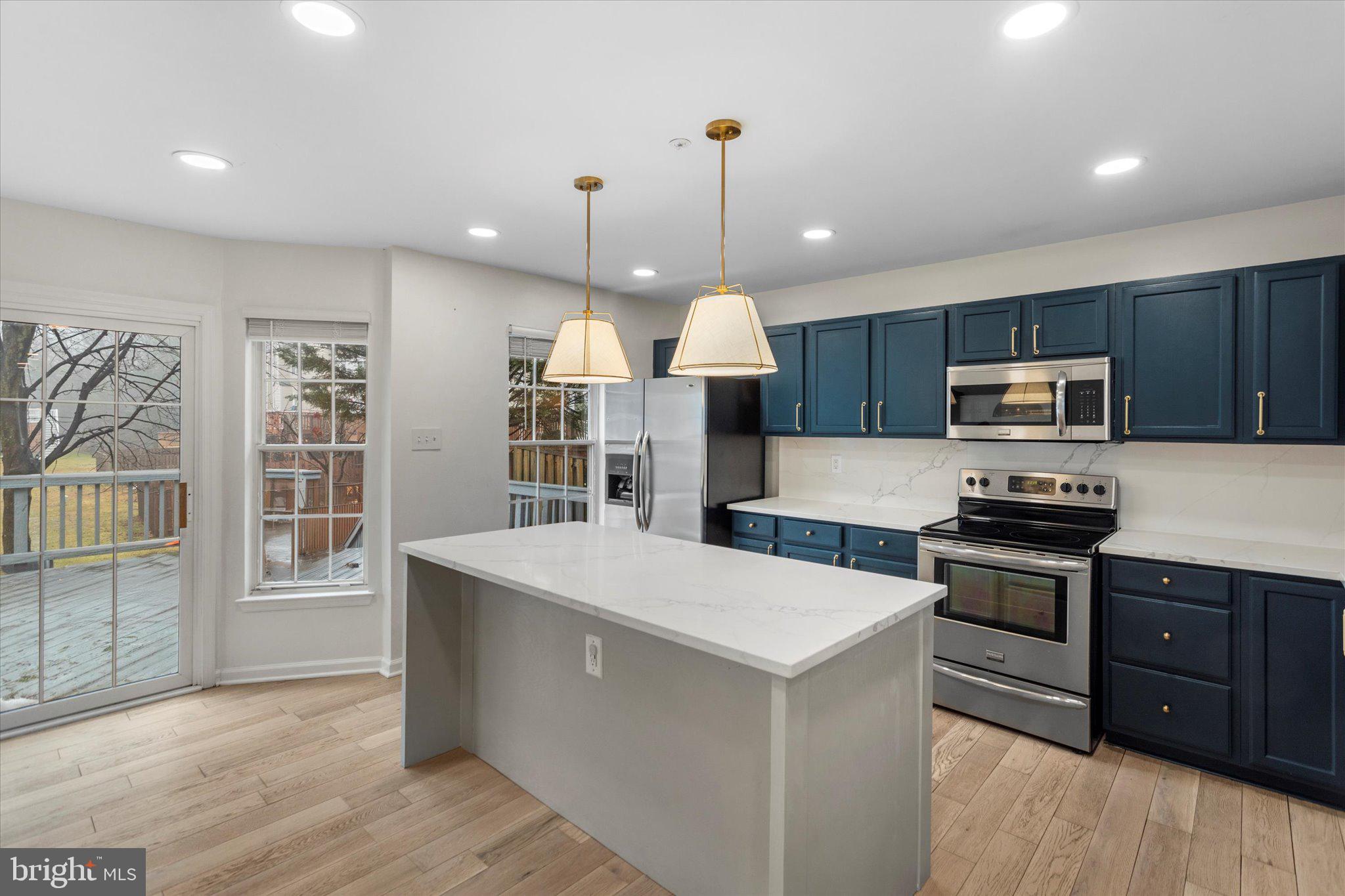 6105 Starburn Path Columbia, MD 21045 - Photo 7 of 30 a kitchen with stainless steel appliances granite countertop a sink stove a refrigerator a center island a stove and a wooden floors