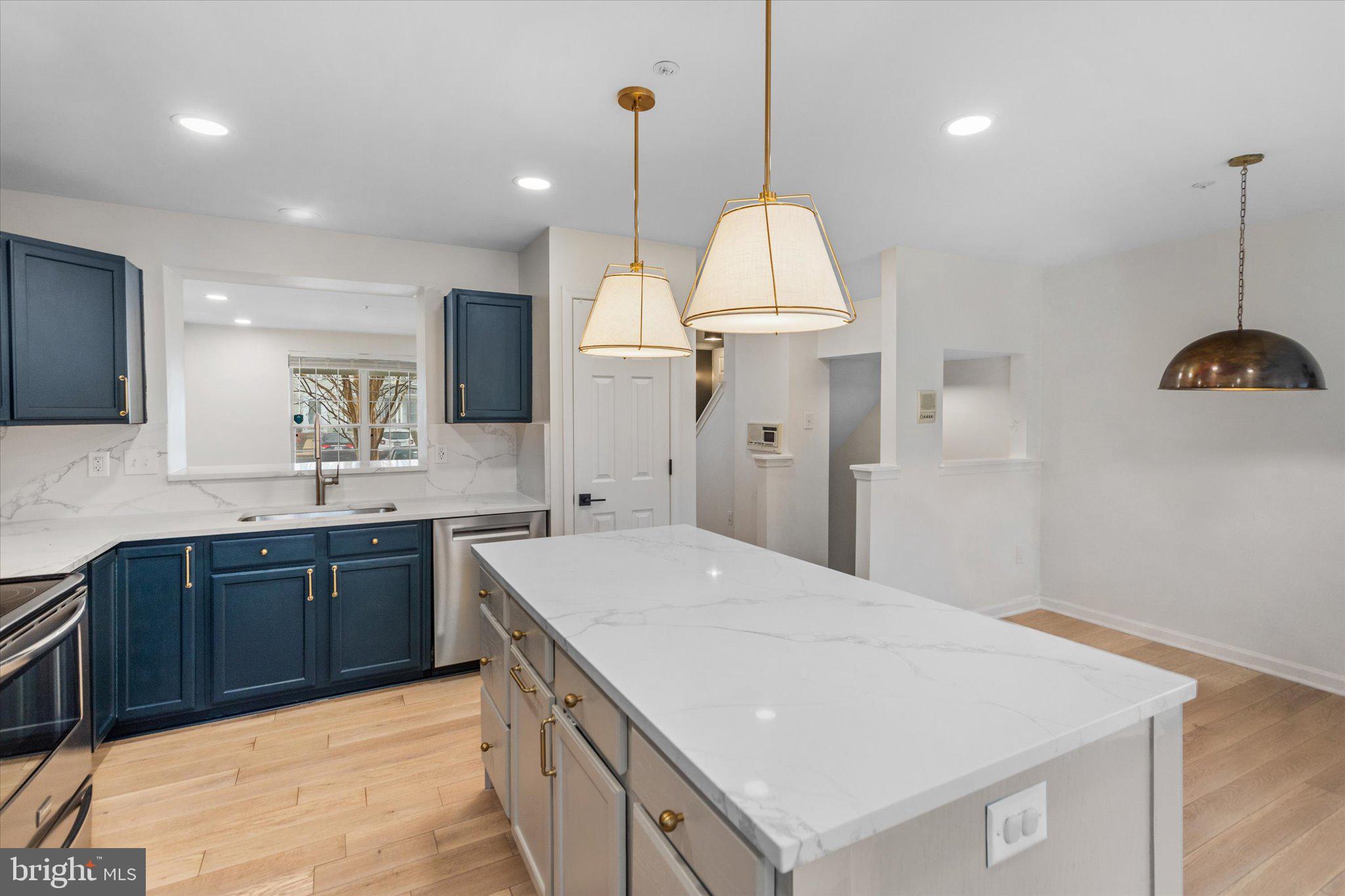 6105 Starburn Path Columbia, MD 21045 - Photo 9 of 30 a large kitchen with kitchen island a stove a sink a center island and a wooden floor