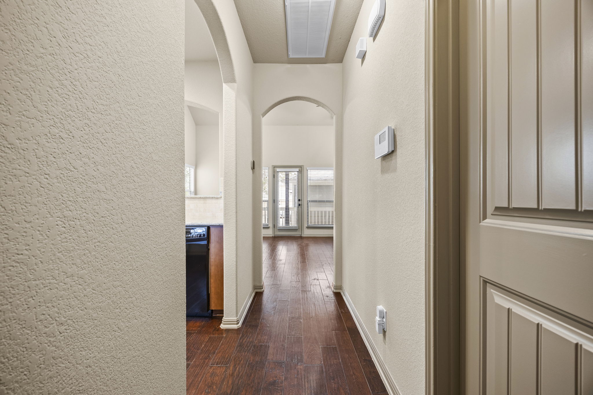 263 Cleveland Kyle, TX 78640 - Photo 3 of 20 Corridor, arched walkways, and dark wood-style floors