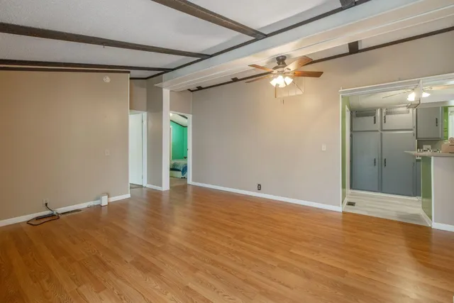 a view of an empty room with wooden floor and a window