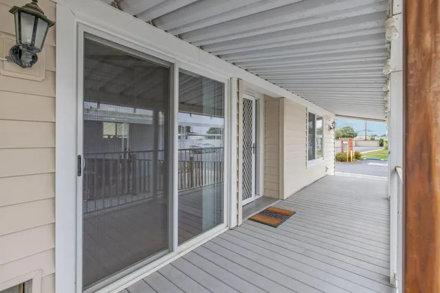 a view of a porch with wooden floor and floor to ceiling window