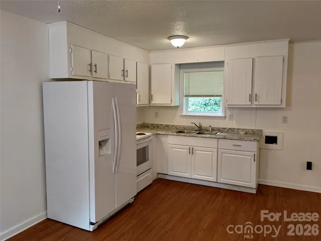 a kitchen with granite countertop white cabinets and white appliances