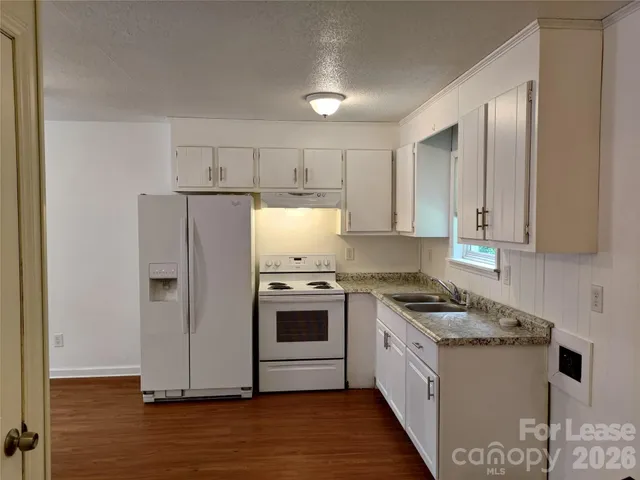 a kitchen with stainless steel appliances a white cabinets and wooden floor