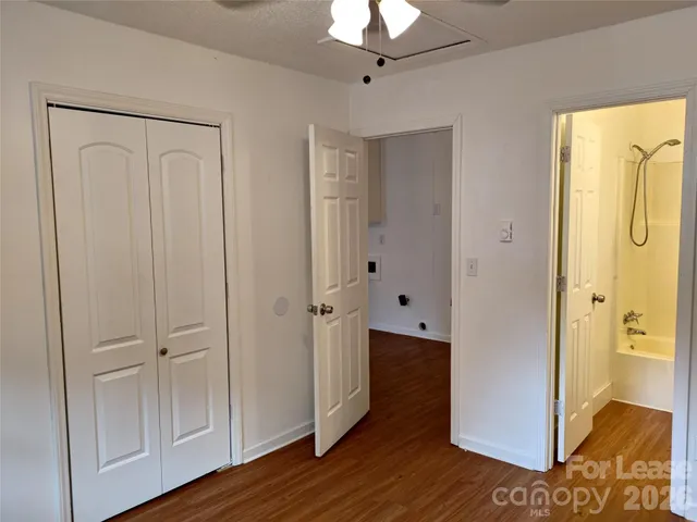a view of an empty room with wooden floor and a bathroom