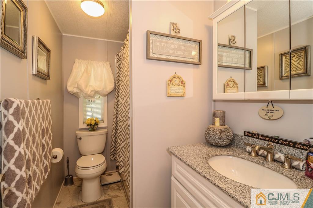 9 Morley Road, Unit 9 North Brunswick, NJ 08902 - Photo 10 of 19 a bathroom with a granite countertop toilet sink and mirror
