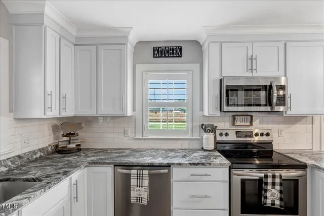 a kitchen with granite countertop a stove sink and microwave