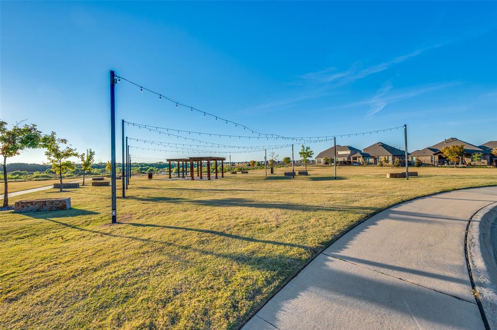 9805 Quail Pointe Road Aubrey, TX 76227 - Photo 36 of 38 Expansive green space featuring a paved walking path, string lighting, and a wooden pergola structure