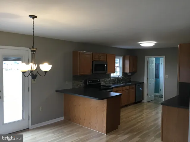 a kitchen with stainless steel appliances granite countertop a sink a stove and a wooden floor