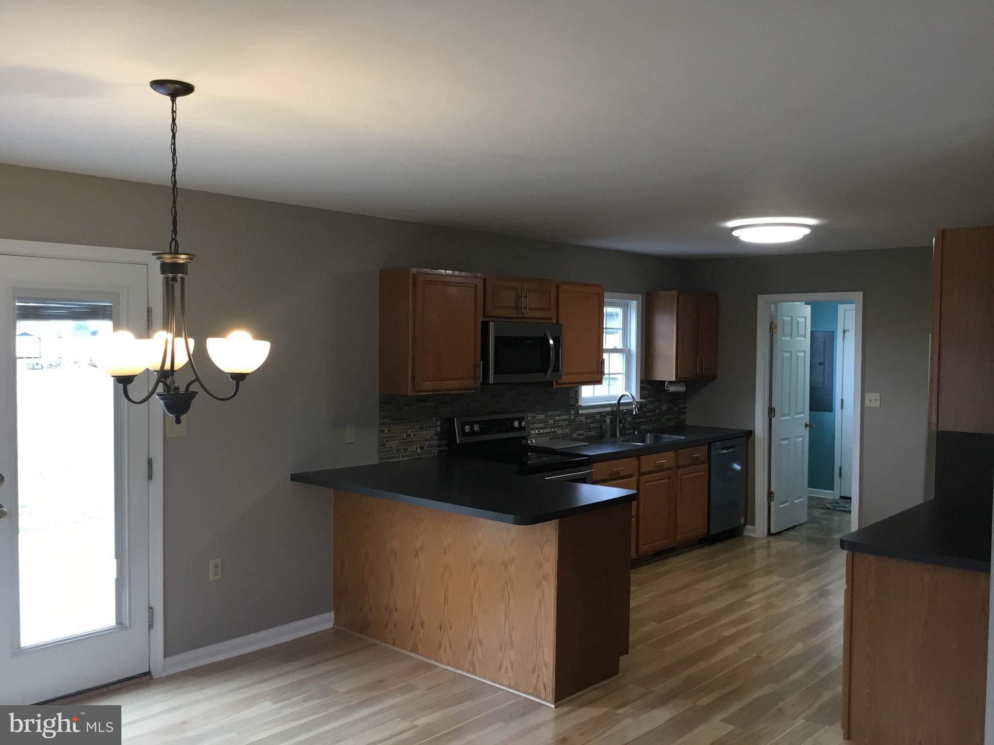 4810 Jacksonville Road Crisfield, MD 21817 - Photo 19 of 38 a kitchen with stainless steel appliances granite countertop a sink a stove and a wooden floor