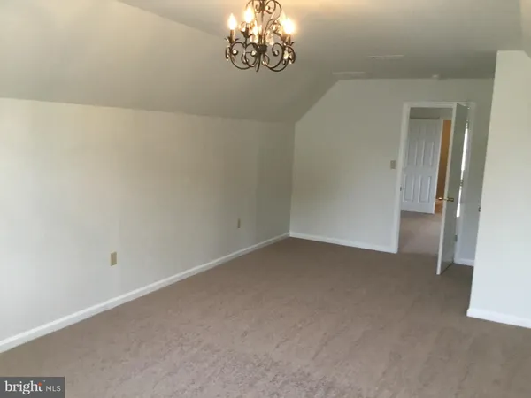 a view of an empty room with a chandelier fan