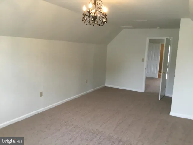 a view of an empty room with a chandelier fan
