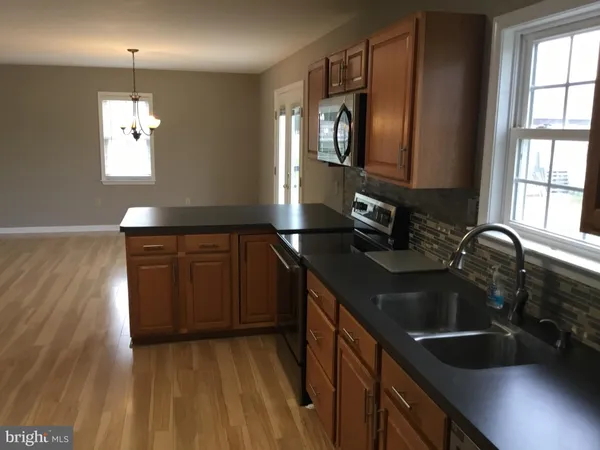 a kitchen with a sink and a stove top oven with wooden floor