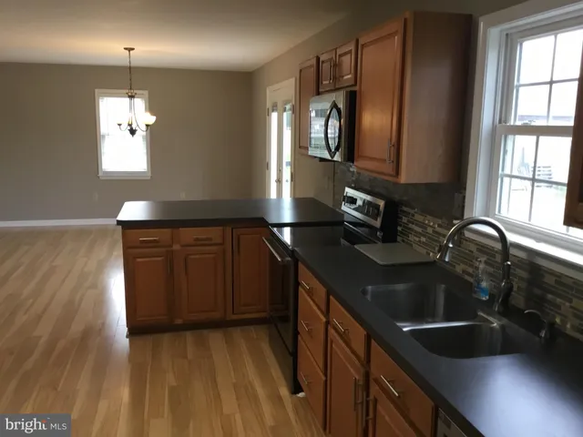 a kitchen with a sink and a stove top oven with wooden floor
