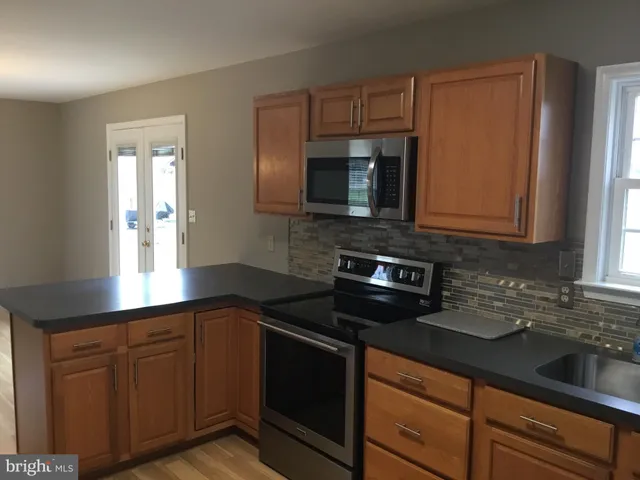a kitchen with granite countertop cabinets stainless steel appliances a sink and wooden floor
