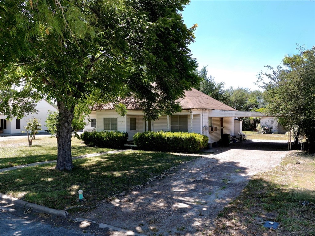 712 East 2nd Street Alice, TX 78332 - Photo 3 of 25 a front view of a house with a garden and trees