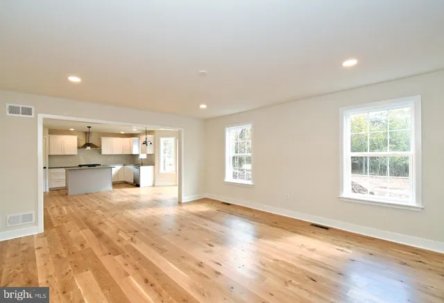 an empty room with wooden floor a fireplace and windows