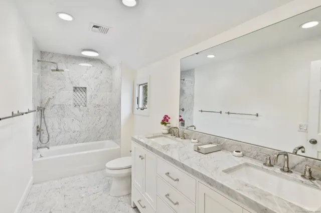 a bathroom with a granite countertop sink a toilet and shower